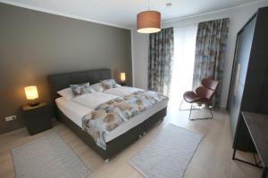 a bedroom with a large bed and a chair at Zentrum Appartements Mörbisch in Mörbisch am See