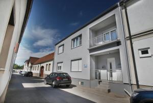 a car parked in front of a white building at Zentrum Appartements Mörbisch in Mörbisch am See