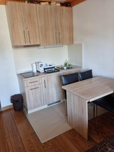 Una cocina con armarios de madera, una mesa y un fregadero. en Apartman 151 U u Aparthotelu Vučko Jahorina - private host, en Jahorina