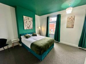 a bedroom with a bed with green walls and a window at Broomfield Place in Spon End
