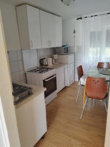 a kitchen with white cabinets and a table and chairs at Apartman Barbara in Cres