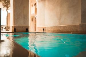 a swimming pool in a building with blue water at Riad Dar Zaouia in Marrakesh