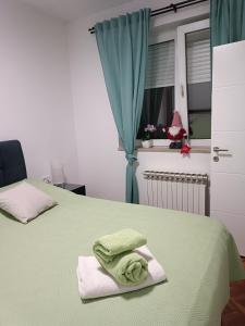 1 dormitorio con 2 camas y toallas verdes. en Apartman na jezeru en Zagreb