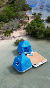 two tables with umbrellas on a beach near the water at Bonnethead Key Floating Campground and Private Island in Key West