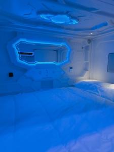 CAPSULE INN VALENCIA Hostel في فالنسيا: سرير في غرفة مع ضوء أزرق