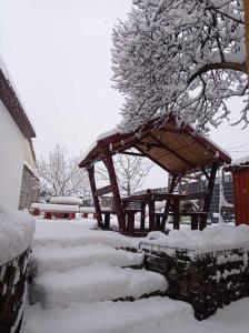 um gazebo de madeira coberto de neve num quintal em BORINA VENDÉGHÁZ em Sátoraljaújhely