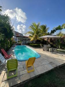 プライア・ドス・カルネイロスにあるBela Casa Praia dos Carneiros Condominio Beira Mar Seg 24hrs FRENTE PISCINAS NATURAIS!!!のスイミングプール(芝生の椅子2脚、椅子2脚付)