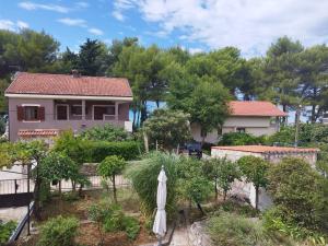 a house with an umbrella in a garden at Apartman Barbara in Cres