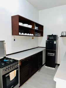 a kitchen with a stove and a refrigerator at WYNE'S COZY 2 BEDROOM IN SHANZU in Mombasa