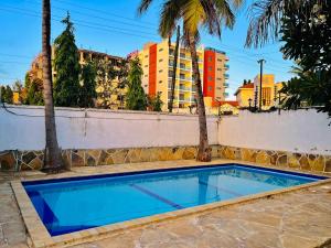 a swimming pool with palm trees and buildings in the background at WYNE'S COZY 2 BEDROOM IN SHANZU in Mombasa +6 photos