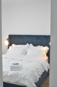 uma cama branca com uma cabeceira azul e almofadas brancas em דירת רויאלטי עם חצר ונוף לשמורת טבע בפסגות אפק em Rosh Ha‘Ayin