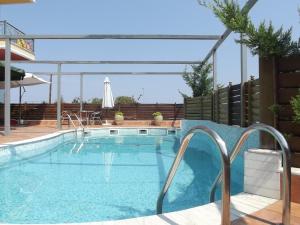 a large swimming pool with a fence and a patio at Hotel Metropole in Leptokarya