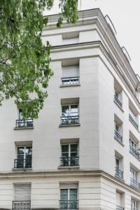 a tall white building with windows and balconies at Lys : Cocon Douillet proche Métro in Montrouge