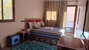 Un dormitorio con una cama con una maleta y una ventana en Riad otos views, en Imlil