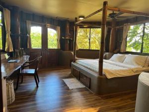 ein Schlafzimmer mit einem Himmelbett und einem Schreibtisch in der Unterkunft Sangat Island Dive Resort in Coron