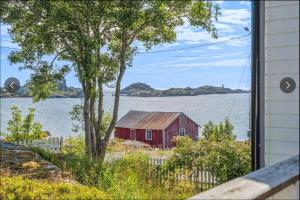 a red barn on the shore of a body of water at Skipperhuset in Sund