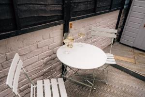 a white table with two chairs and two glasses of wine at Sanctuary-by-Sea in Worthing +32 photos
