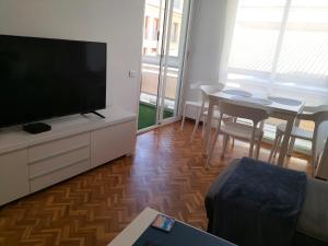 uma sala de estar com uma televisão de ecrã plano e uma mesa em Alexander Apartments em Alicante