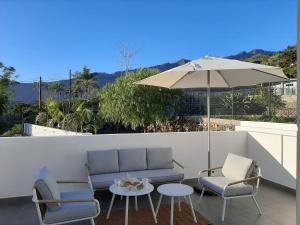 un patio con divano, sedie e ombrellone di Casa Argeo a Los Llanos de Aridane