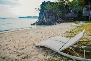 a white lounge chair sitting on a beach at Sangat Island Dive Resort in Coron