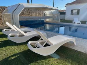 twee witte ligstoelen naast een zwembad bij Solar das Mimosas 2 casas in Sintra