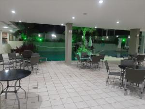a restaurant with tables and chairs and a pool at Rio Quente-GO SERRA PARK com 2 camas de casal in Rio Quente