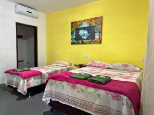 2 camas en una habitación con paredes amarillas en Encanto do Parque Hospedagem, en Lençóis