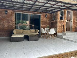 un patio con sofá, mesa y sillas en Acuvea Inn, en Kempton Park