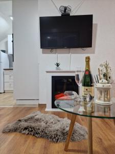 ein Wohnzimmer mit einem Glastisch und einer Flasche Wein in der Unterkunft Apartments Gradiska in Bosanska Gradiška