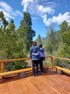 dos personas de pie en una cubierta mirando a las montañas en Casa Conguillio en Melipeuco, en Melipeuco