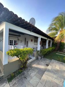 ein weißes Haus mit einer Terrasse und einer Palme in der Unterkunft Bela Casa Praia dos Carneiros Condominio Beira Mar Seg 24hrs FRENTE PISCINAS NATURAIS!!! in Praia dos Carneiros