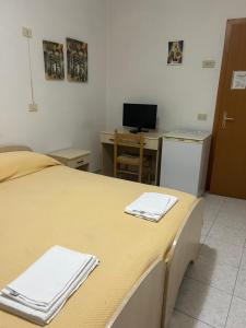 a room with a bed and a desk with a computer at Albergo pensione Bianco in San Giovanni Rotondo