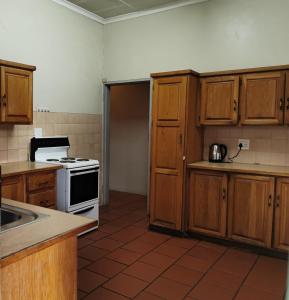 a kitchen with wooden cabinets and a stove top oven at GLESTER GUEST HOUSE in Pretoria