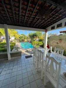 eine Terrasse mit einem Tisch und Stühlen sowie einem Pool in der Unterkunft Bela Casa Praia dos Carneiros Condominio Beira Mar Seg 24hrs FRENTE PISCINAS NATURAIS!!! in Praia dos Carneiros