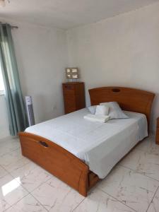 a bedroom with a large wooden bed with white sheets at Casa Graciosa in Tarrafal