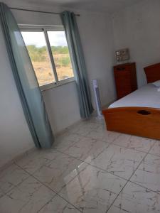 a bedroom with a bed and a window and a tiled floor at Casa Graciosa in Tarrafal