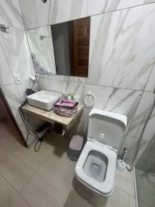ein Badezimmer mit einem Waschbecken, einem WC und einem Spiegel in der Unterkunft Villa Amarelo in Beberibe