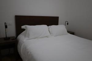 - un lit blanc avec des oreillers blancs dans une chambre dans l'établissement Hotel Mado, à Jalostotitlán