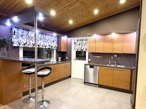 a kitchen with wooden cabinets and a bar with stools at Linnunvilla with sauna in Rovaniemi
