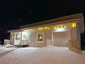 a house with a garage in the snow at night at Linnunvilla with sauna in Rovaniemi