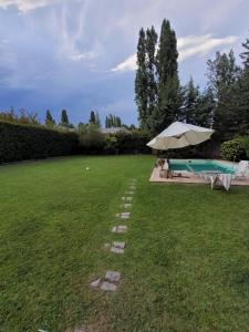 a lawn with an umbrella and a swimming pool at Rincón Verde Chacras de Coria in Ciudad Lujan de Cuyo