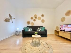 a living room with a black couch and a tv at LA PASSERELLE 2G - Quartier Gare - Wifi - Parking in Quimper