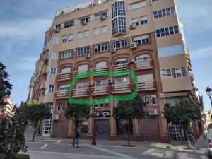 Un edificio alto con una señal verde. en "El Balcón de Huelva" lujo en pleno centro, en Huelva