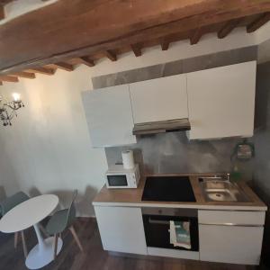 a kitchen with white cabinets and a sink and a table at piccolo Garibaldi appartamento in Arezzo