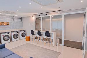 a laundry room with three washing machines and stools at Blend Smart Marista 2 Quartos in Goiânia