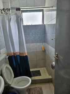 a bathroom with a shower curtain and a toilet at Waridi house in Ongata Rongai 