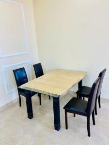 una mesa de madera con sillas negras y una mesa de madera con en Al seeb beach appartements, en Seeb