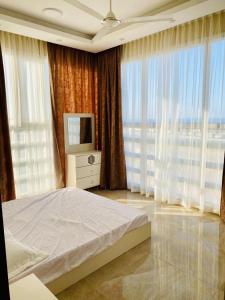 1 dormitorio con 1 cama, TV y ventanas en Al seeb beach appartements, en Seeb