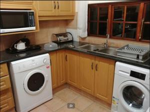 a kitchen with a washing machine and a sink at Fairways resort 6 sleeper unit in Drakensberg Garden