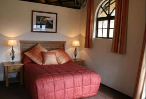 a bedroom with a red bed with two tables and two lamps at Fairways resort 6 sleeper unit in Drakensberg Garden